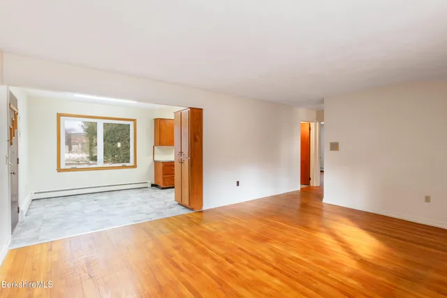 a view of an empty room with window and wooden floor