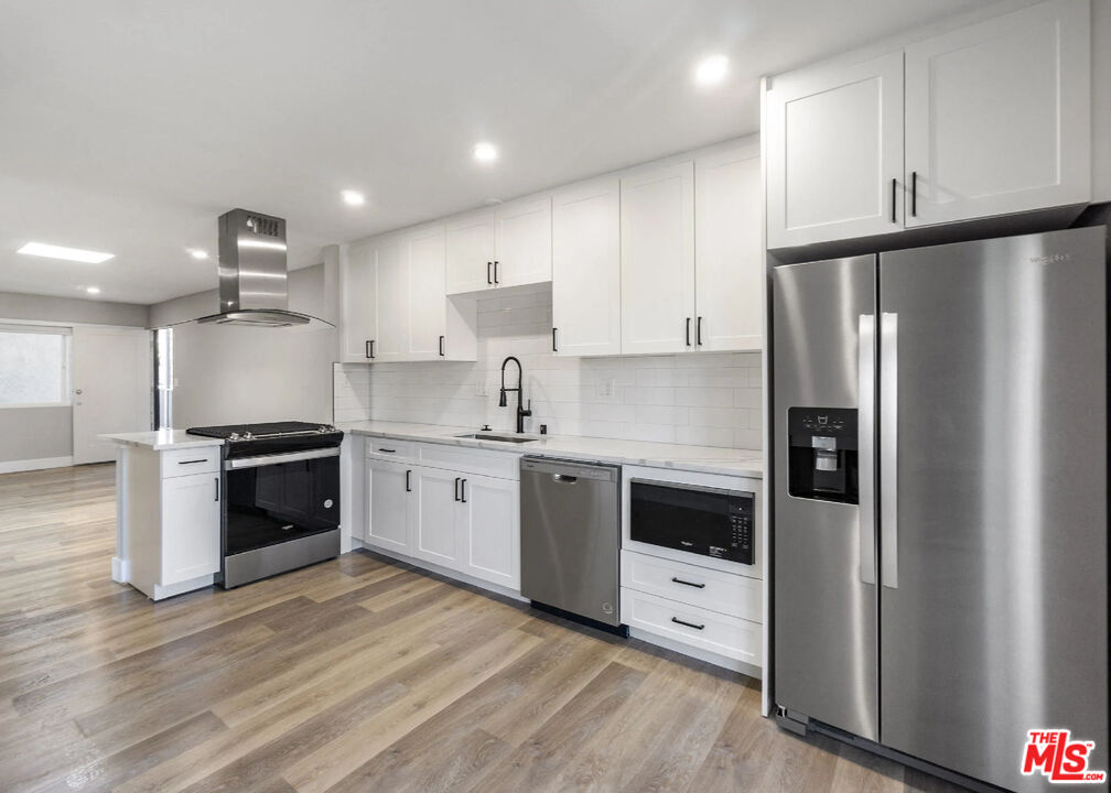 125 16th Street Huntington Beach, CA 92648 - Photo 7 of 10 a kitchen with stainless steel appliances white cabinets and wooden floors