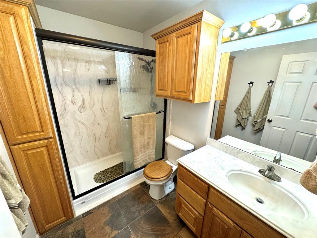 505 3rd Street Dodd City, TX 75438 - Photo 36 of 37 a bathroom with a sink a toilet a mirror and shower
