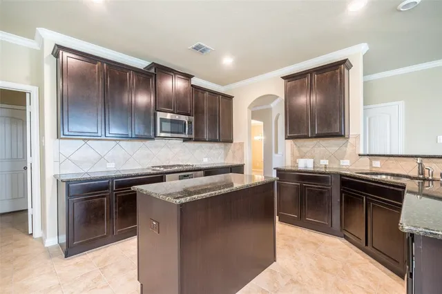 a kitchen with kitchen island granite countertop stainless steel appliances and wooden cabinets