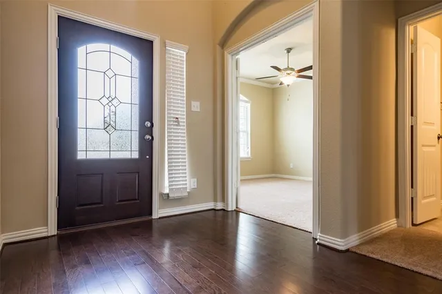 an empty room with wooden floor cabinet and windows