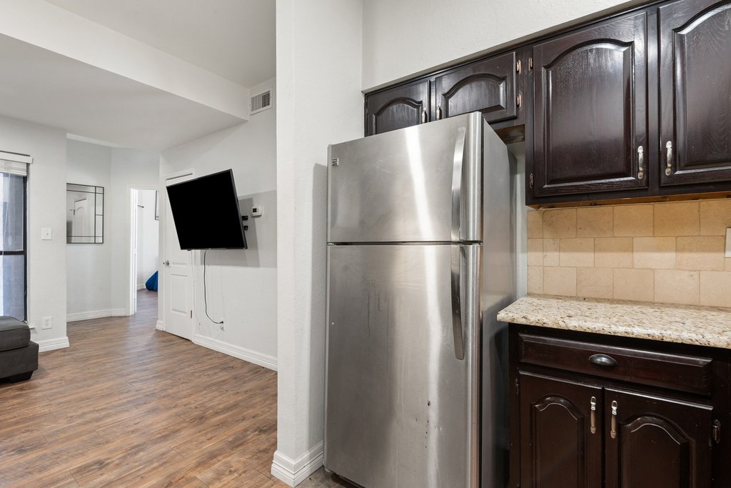 1910 Robbins Place, Unit 106 Austin, TX 78705 - Photo 6 of 20 a kitchen with stainless steel appliances granite countertop a refrigerator microwave and sink