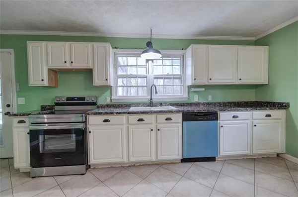 a kitchen with granite countertop a stove sink and cabinets