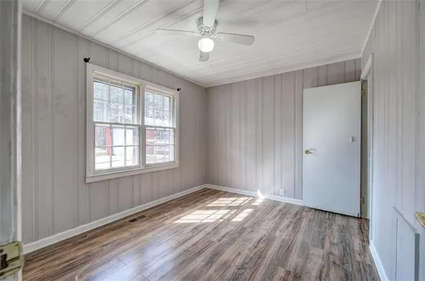 a view of empty room with wooden floor and fan