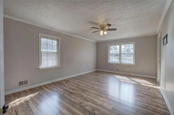 an empty room with wooden floor ceiling fan and windows