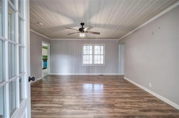 a view of an empty room with window and wooden floor