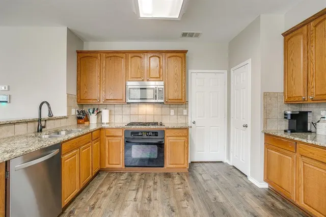 a kitchen with granite countertop a refrigerator stove top oven and sink