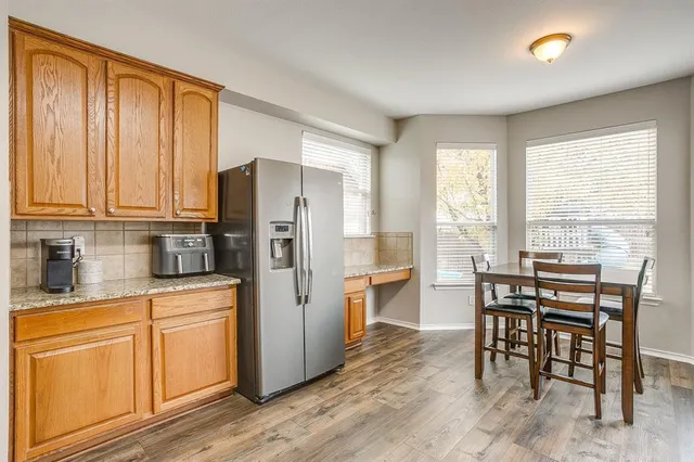 a kitchen with stainless steel appliances granite countertop a stove top oven a sink dishwasher and a refrigerator with wooden floor