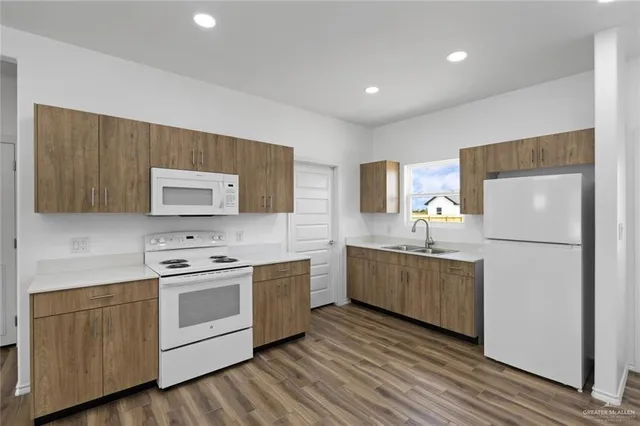 a kitchen with a white cabinets a sink dishwasher and a stove with wooden floor