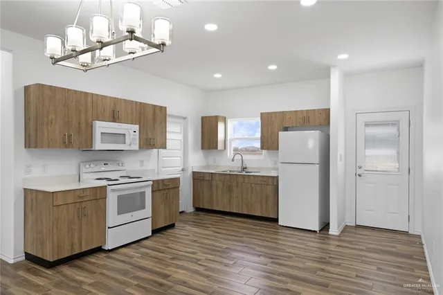 a kitchen with a sink stainless steel appliances wooden floor and chandelier