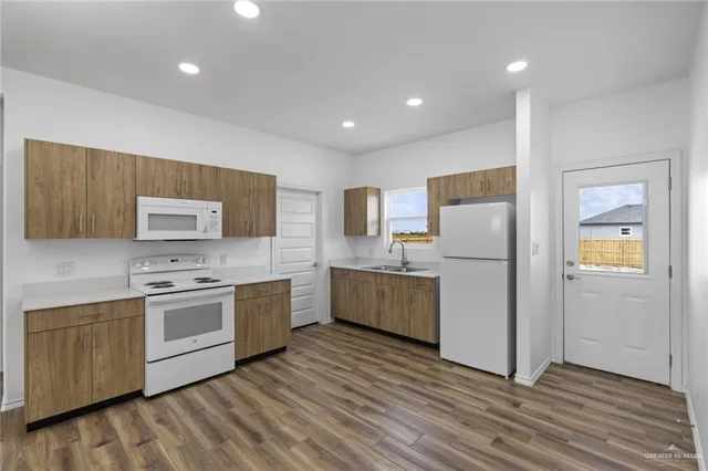 a kitchen with a sink a refrigerator and wooden floor