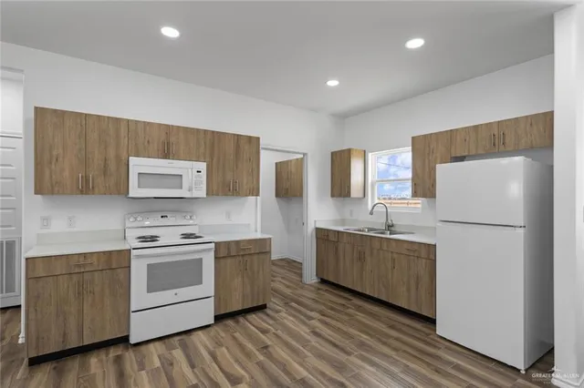 a kitchen with stainless steel appliances a sink cabinets and wooden floor