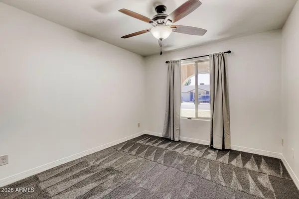 an empty room with a chandelier fan and windows