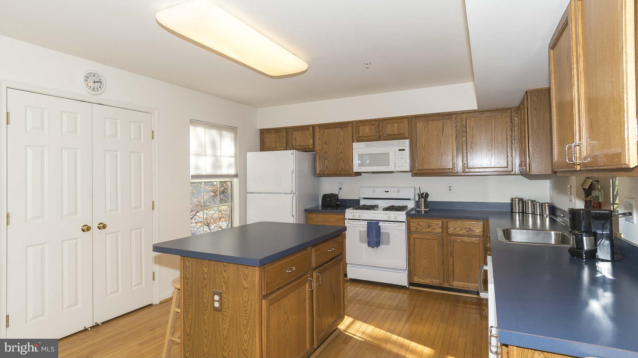 12200 Bare Bush Path Columbia, MD 21044 - Photo 12 of 30 a kitchen with stainless steel appliances granite countertop a stove a sink a refrigerator white cabinets with wooden floor