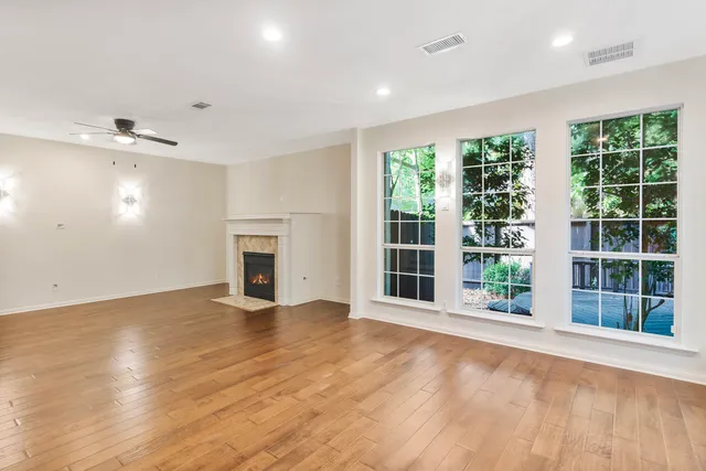 a view of an empty room with a window and wooden floor
