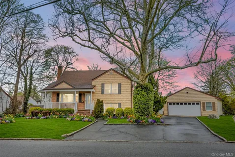 a front view of a house with a garden and trees