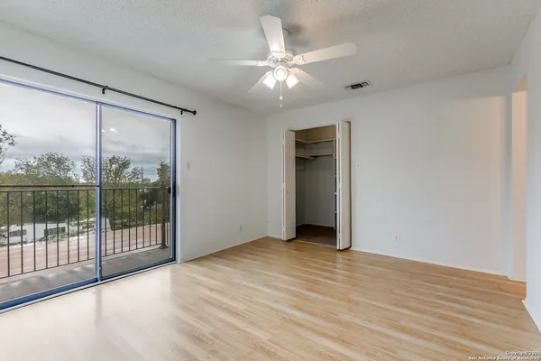 a view of an empty room with wooden floor and closet