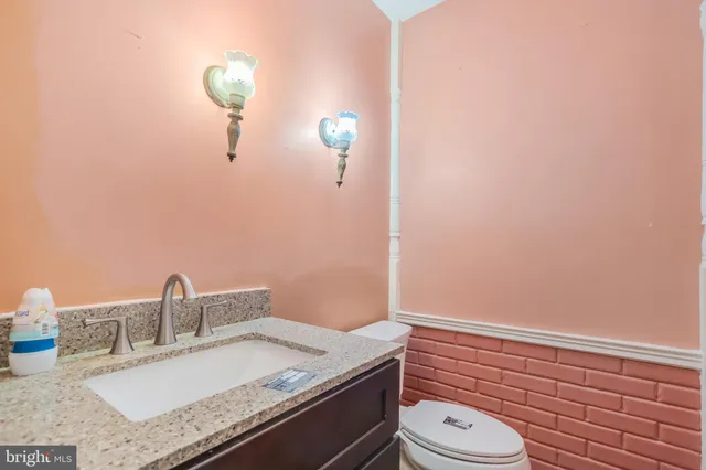 a bathroom with a granite countertop sink toilet and mirror