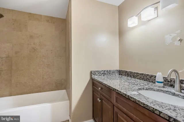 a bathroom with a granite countertop sink and a bathtub