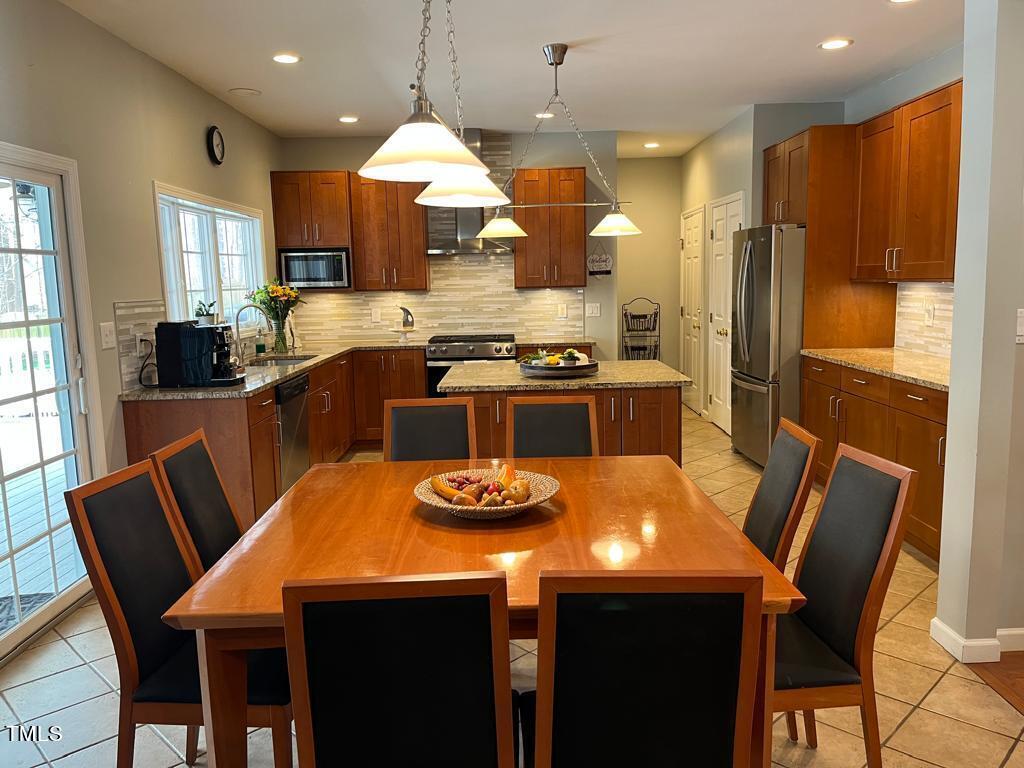 103 Summerglow Court Cary, NC 27513 - Photo 19 of 67 a kitchen with stainless steel appliances granite countertop a dining table chairs stove refrigerator and cabinets