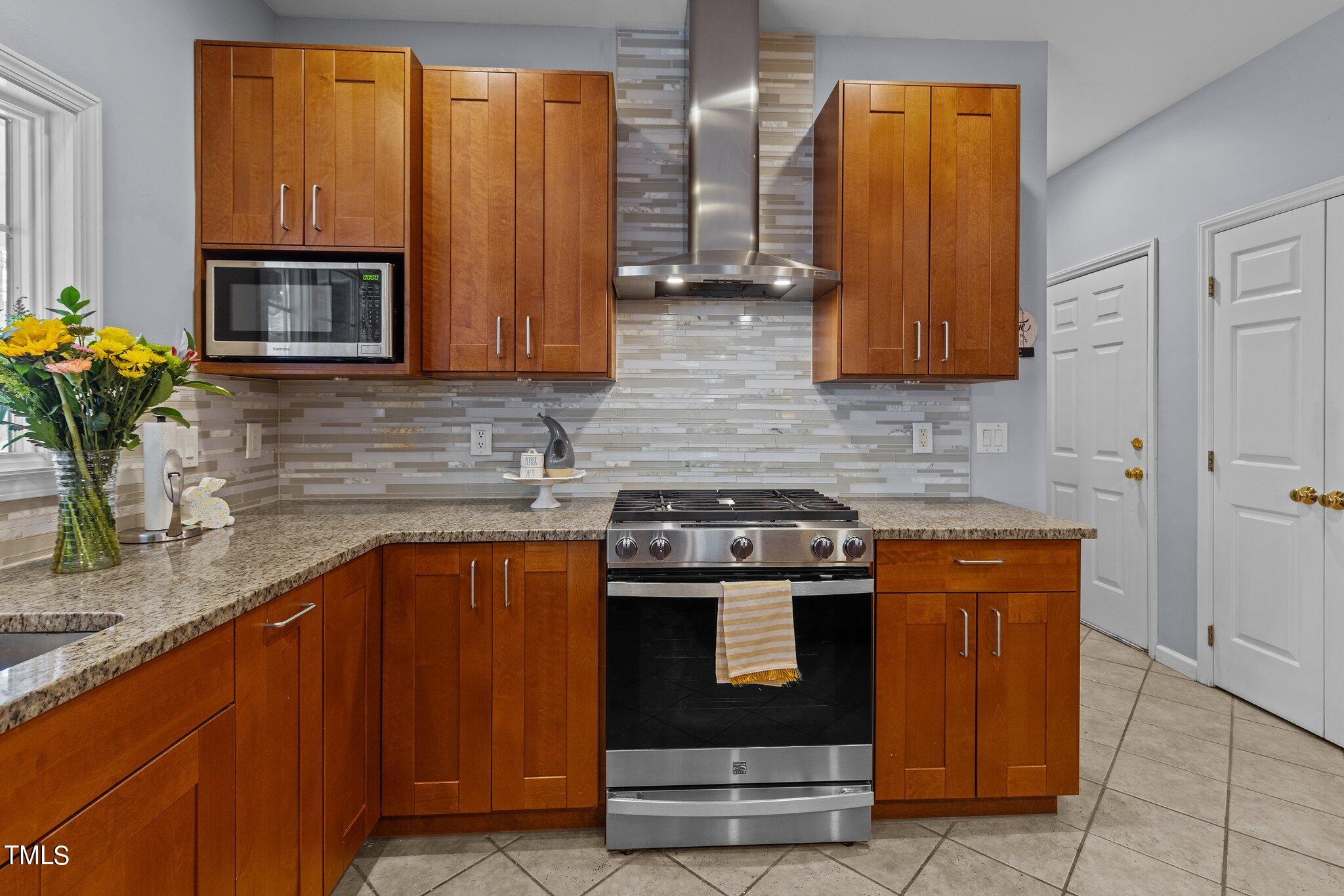 103 Summerglow Court Cary, NC 27513 - Photo 23 of 67 a kitchen with stainless steel appliances wooden cabinets and a stove top oven