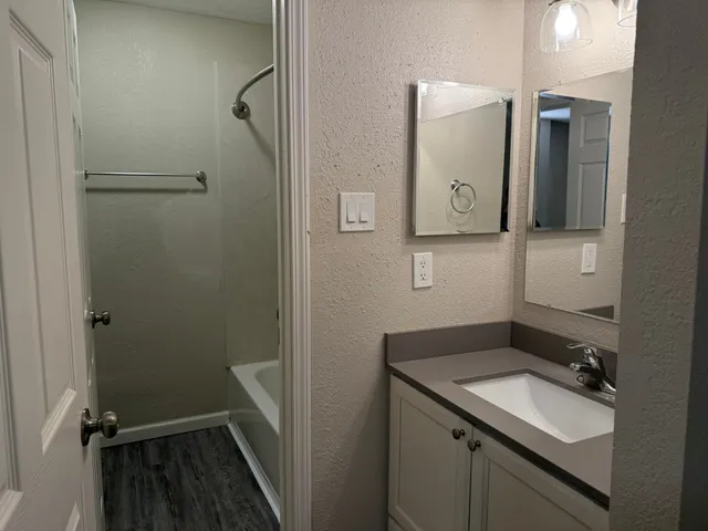 a bathroom with a shower sink vanity and mirror