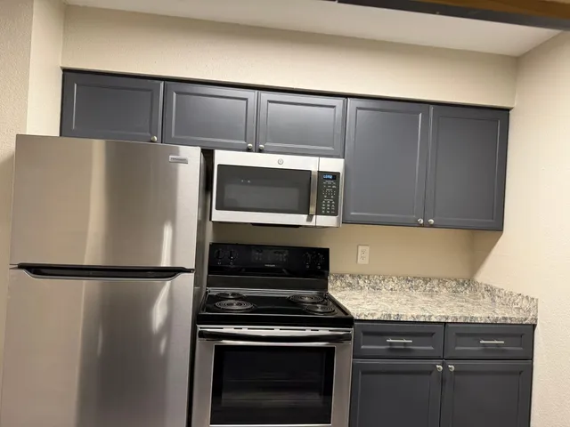 a kitchen with granite countertop a refrigerator stove and microwave