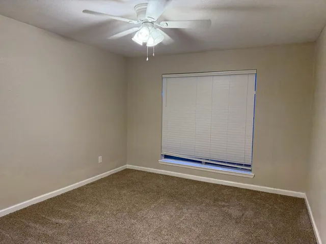 an empty room with a fan & a window