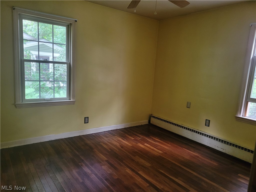 7357 Westview Road Kent, OH 44240 - Photo 20 of 30 Empty room featuring plenty of natural light, dark hardwood / wood-style floors, ceiling fan, and a baseboard heating unit