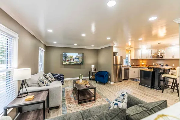 a living room with furniture kitchen view and a wooden floor
