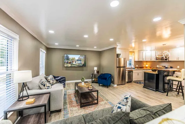a living room with furniture kitchen view and a wooden floor