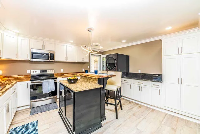 a kitchen with stainless steel appliances granite countertop a stove top oven a sink dishwasher and a refrigerator with wooden floor