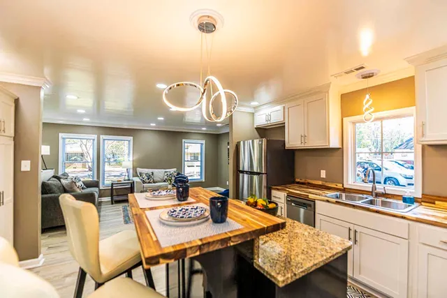 a view of a dining room and livingroom with furniture wooden floor a rug a fireplace and a chandelier