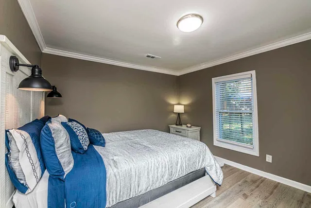 a bedroom with a bed and a lamp on dresser