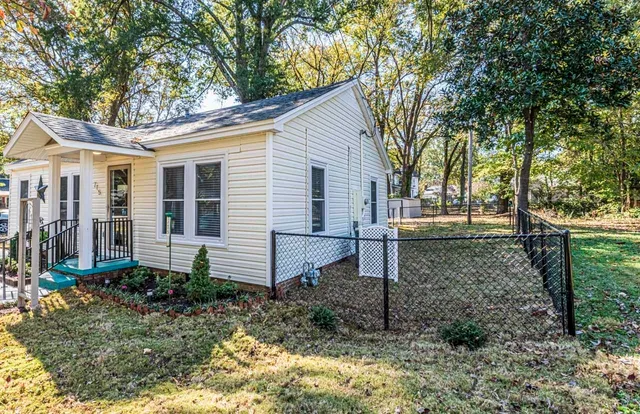 a view of a house with a yard and large trees