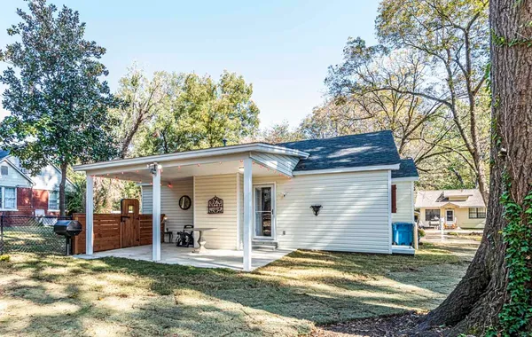 a view of a house with a yard chairs and floor to ceiling window and a yard