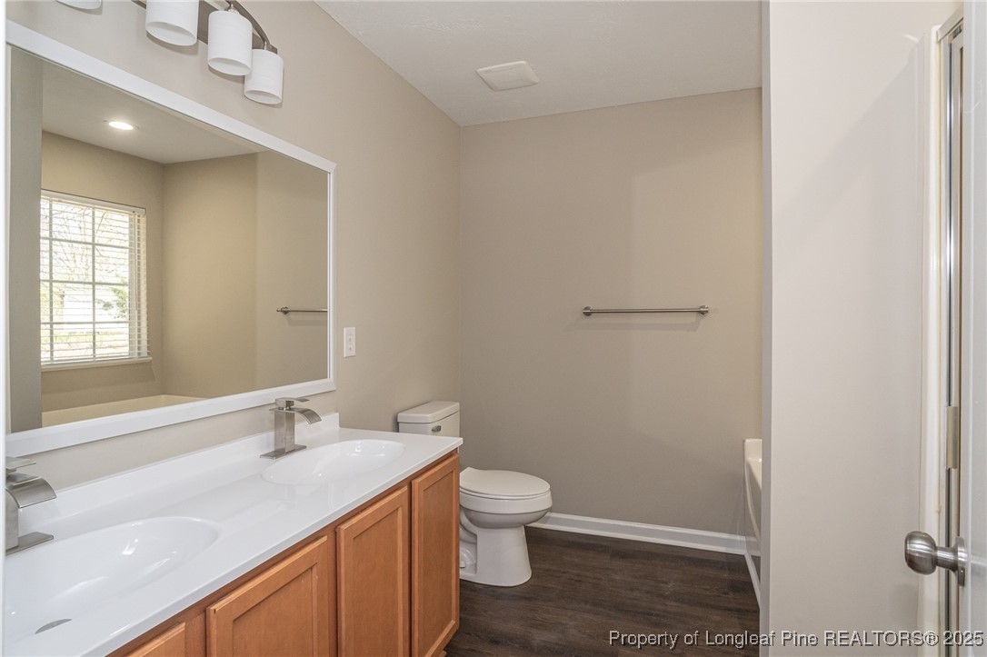 2830 John McMillan Road Hope Mills, NC 28348 - Photo 30 of 46 a bathroom with a granite countertop sink a toilet and a large mirror