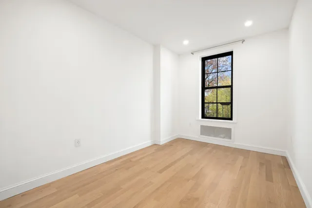 a large white kitchen with window and stainless steel appliances