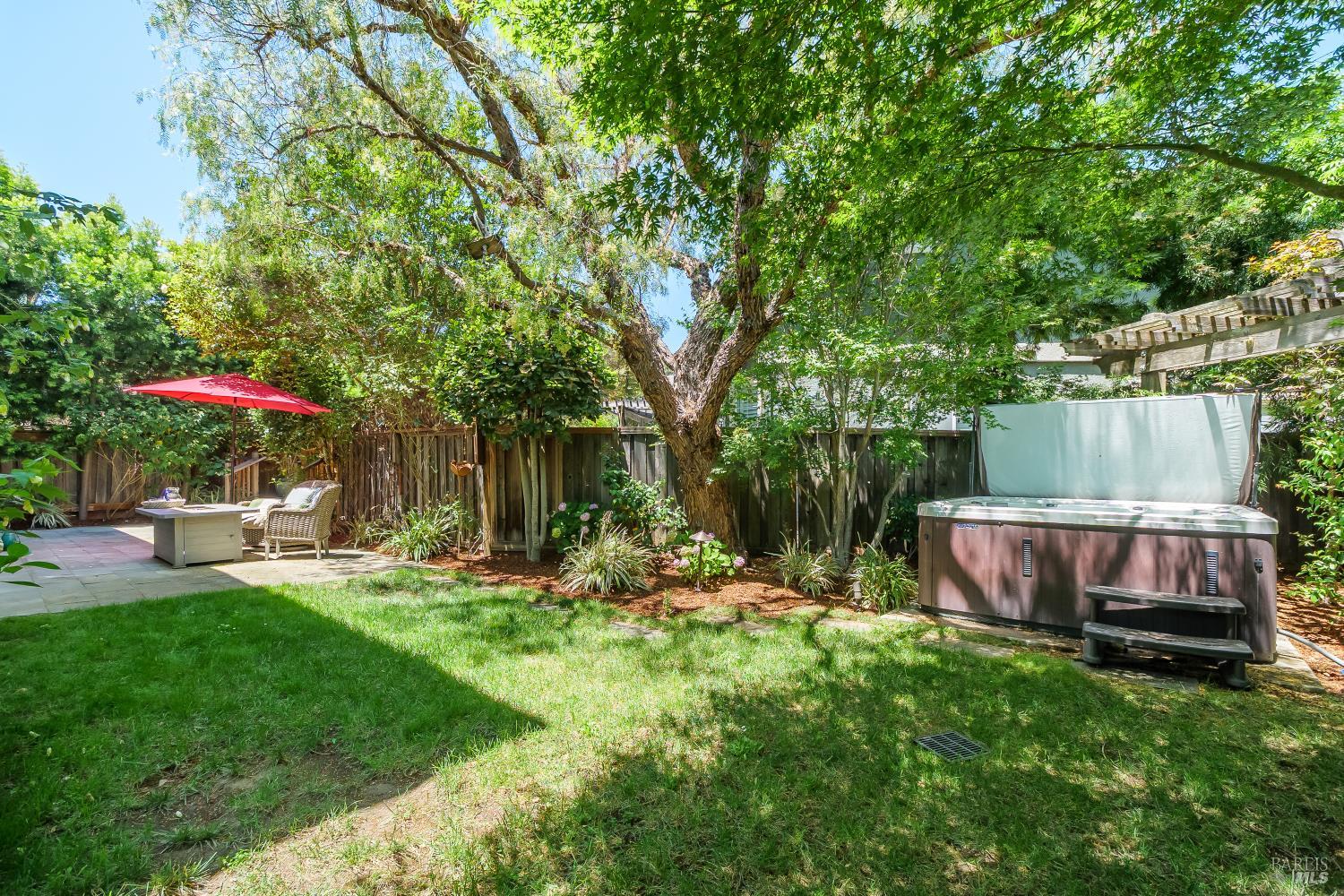 68 Pinheiro Circle Novato, CA 94945 - Photo 29 of 82 The private backyard offers a lush lawn, mature trees, and a hot tub tucked beneath a peaceful canopy of greenery. Designed for both entertaining and unwinding, this outdoor retreat feels private and serene.