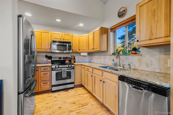 a kitchen with stainless steel appliances granite countertop a stove a sink and a microwave