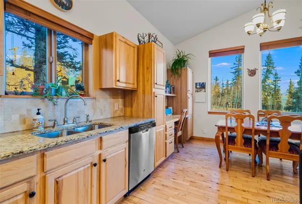 a kitchen with stainless steel appliances granite countertop a stove a sink and a dining table view
