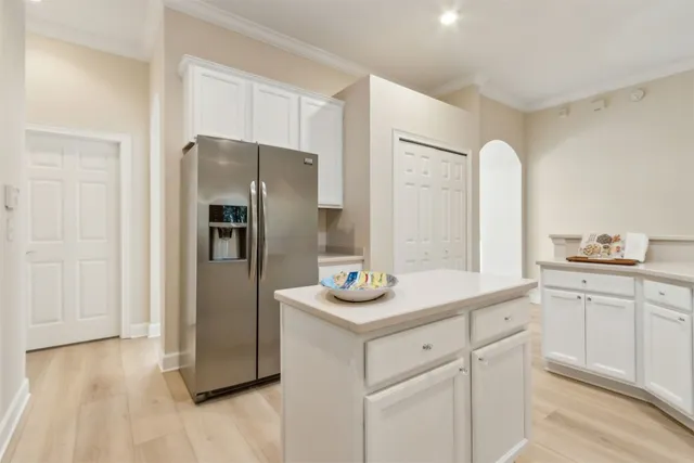 a kitchen with stainless steel appliances kitchen island granite countertop a sink a stove and white cabinets with wooden floor