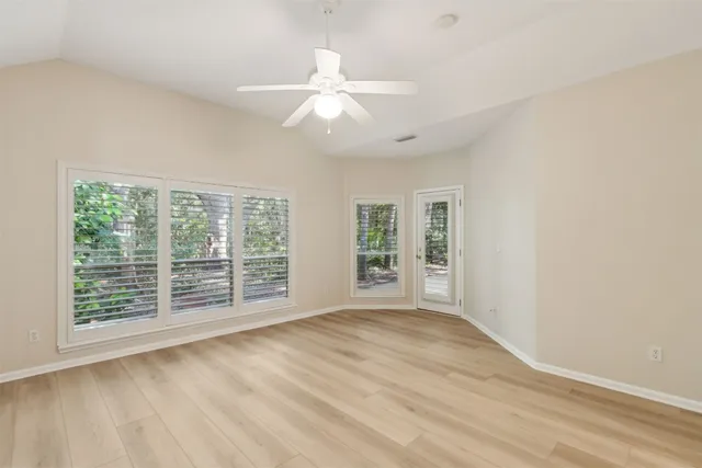 an empty room with wooden floor fan and windows