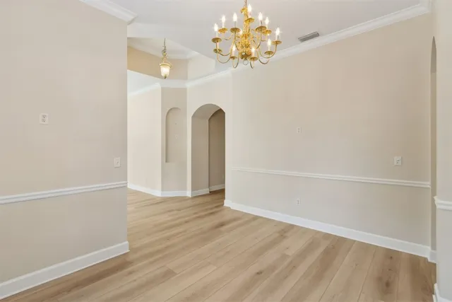 an empty room with wooden floor and chandelier