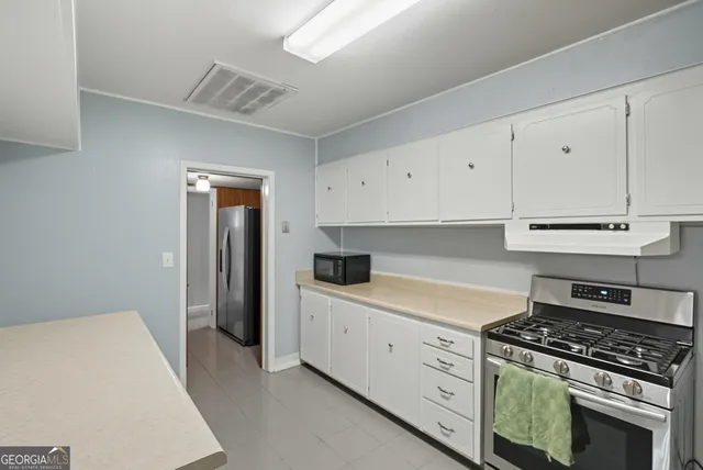 a kitchen with white cabinets and appliances