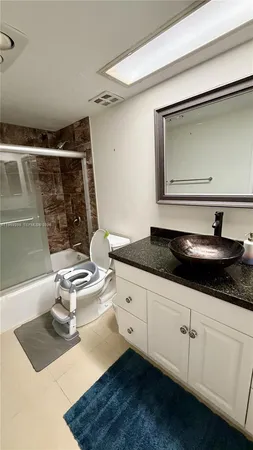 a spacious bathroom with a granite countertop sink a toilet a mirror and shower