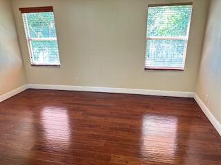 6075 Adriatic Way Greenacres, FL 33413 - Photo 18 of 24 a view of an empty room with wooden floor and a window