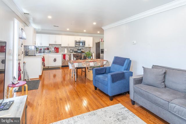 a living room with stainless steel appliances kitchen island granite countertop furniture wooden floor and a kitchen view
