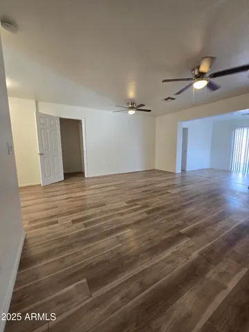 a view of an empty room with window and a chandelier fan