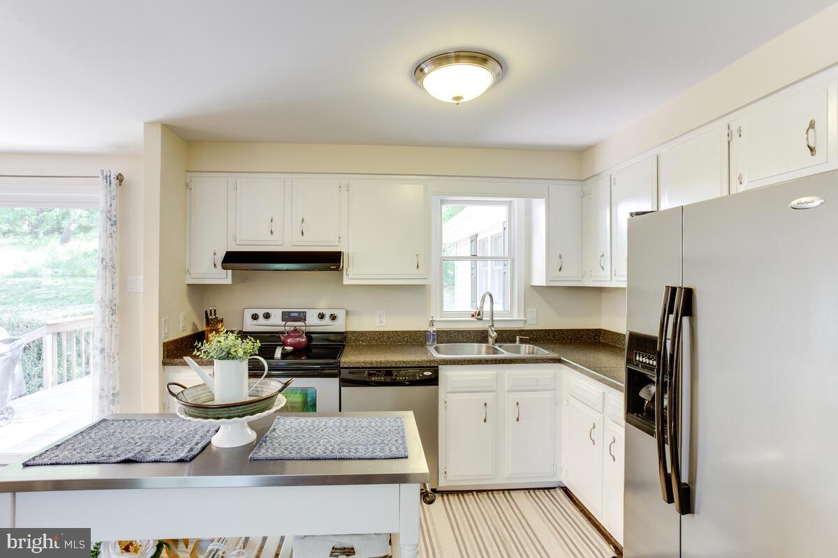 1260 Coster Road Lusby, MD 20657 - Photo 18 of 46 a kitchen with stainless steel appliances granite countertop a sink stove refrigerator and white cabinets with wooden floor